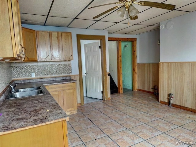 kitchen with sink, light brown cabinets, tasteful backsplash, a paneled ceiling, and wooden walls