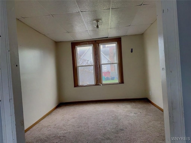 carpeted empty room featuring a paneled ceiling