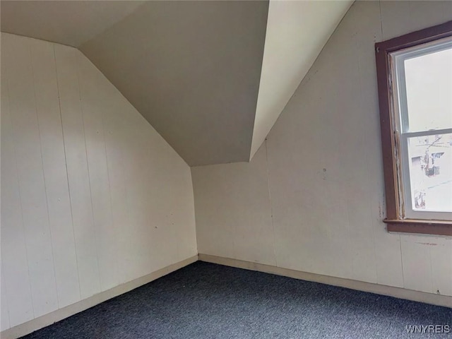 bonus room with a healthy amount of sunlight, dark carpet, and vaulted ceiling