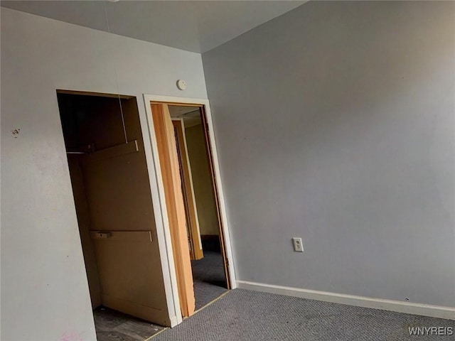 unfurnished bedroom featuring dark carpet and a closet