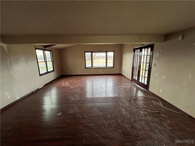 spare room with beamed ceiling and dark wood-type flooring