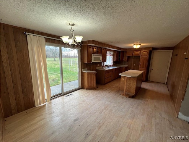 kitchen featuring wooden walls, light hardwood / wood-style flooring, a kitchen island, and hanging light fixtures