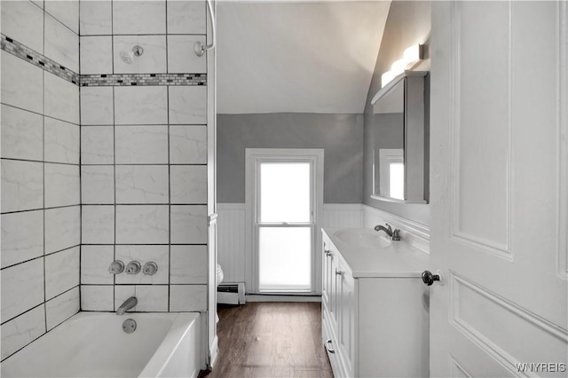 bathroom featuring hardwood / wood-style floors, vanity, vaulted ceiling, tiled shower / bath combo, and a baseboard radiator