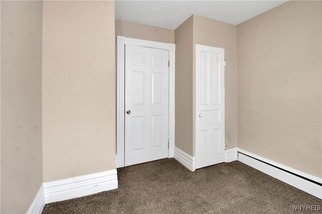 unfurnished bedroom featuring a closet, dark carpet, and a baseboard heating unit