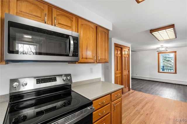 kitchen featuring appliances with stainless steel finishes, a baseboard radiator, and light hardwood / wood-style flooring