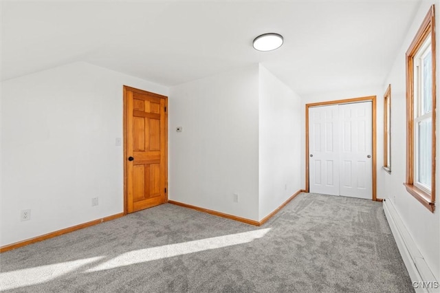 empty room with light carpet, lofted ceiling, and a baseboard heating unit