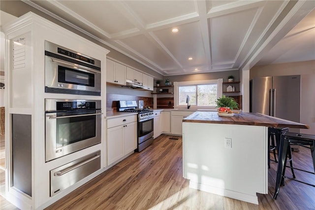 kitchen with white cabinets, stainless steel appliances, a kitchen island, and coffered ceiling