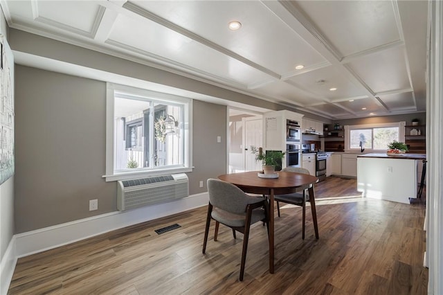 dining room with beamed ceiling, wood-type flooring, a wall unit AC, and coffered ceiling