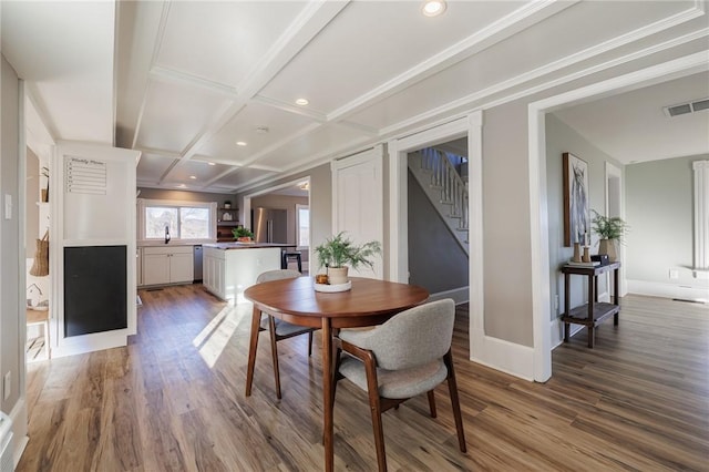 dining space with beam ceiling, coffered ceiling, and hardwood / wood-style flooring