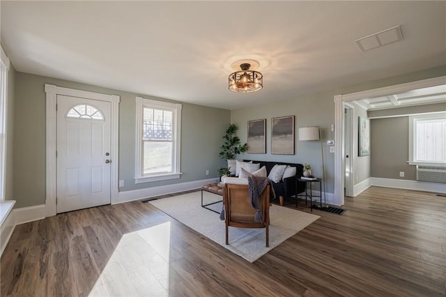 interior space featuring dark hardwood / wood-style floors, a wall unit AC, and plenty of natural light