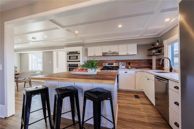 kitchen featuring stainless steel appliances, butcher block countertops, white cabinetry, and plenty of natural light