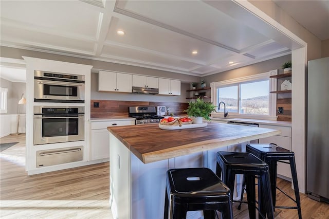 kitchen featuring a kitchen breakfast bar, white cabinetry, a center island, and wooden counters