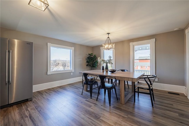 dining area with dark hardwood / wood-style floors and a notable chandelier