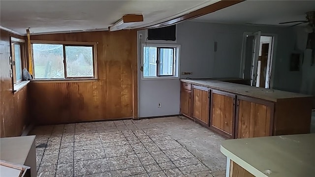 kitchen with ceiling fan, wooden walls, and vaulted ceiling