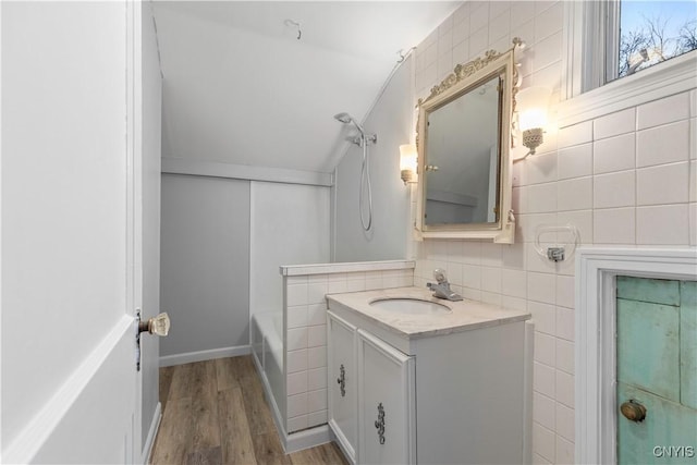 bathroom featuring backsplash, vanity, wood-type flooring, and tile walls