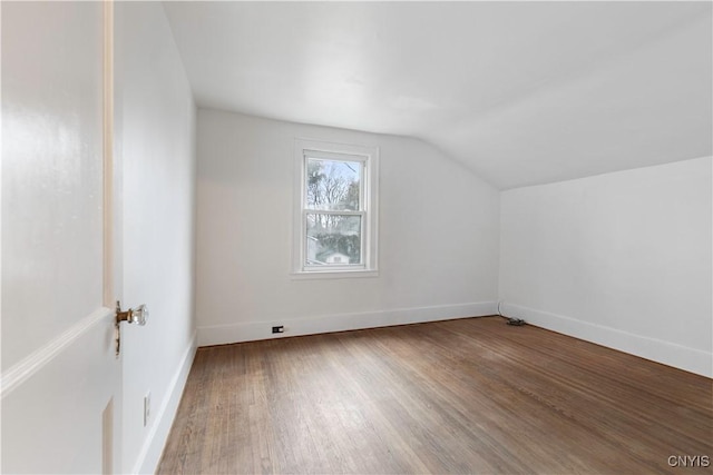 additional living space with hardwood / wood-style flooring and vaulted ceiling