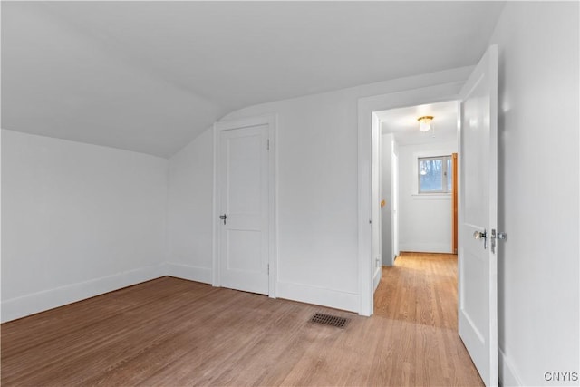 bonus room with light wood-type flooring and vaulted ceiling