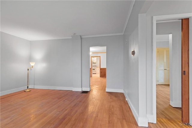 empty room featuring light wood-type flooring and crown molding