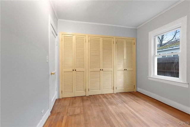 unfurnished bedroom with a closet, ornamental molding, and light hardwood / wood-style flooring