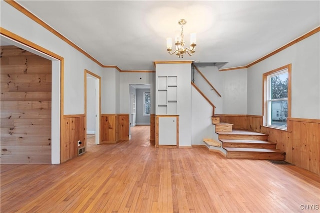 interior space featuring a chandelier, light hardwood / wood-style flooring, wooden walls, and crown molding