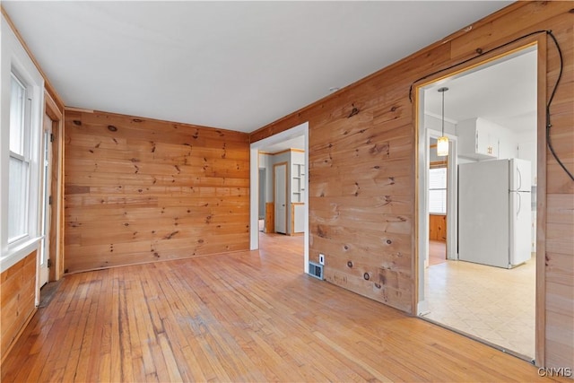 spare room featuring wood walls and light wood-type flooring