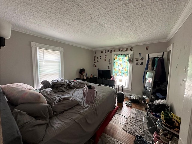 bedroom with wood-type flooring, a textured ceiling, and ornamental molding