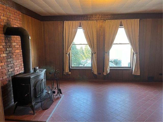 unfurnished living room with wood walls, a wood stove, and a wealth of natural light