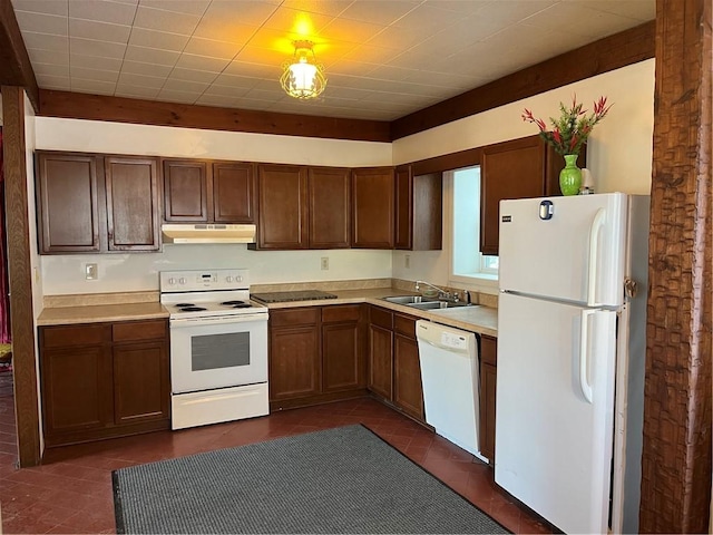 kitchen with dark tile patterned flooring, white appliances, and sink