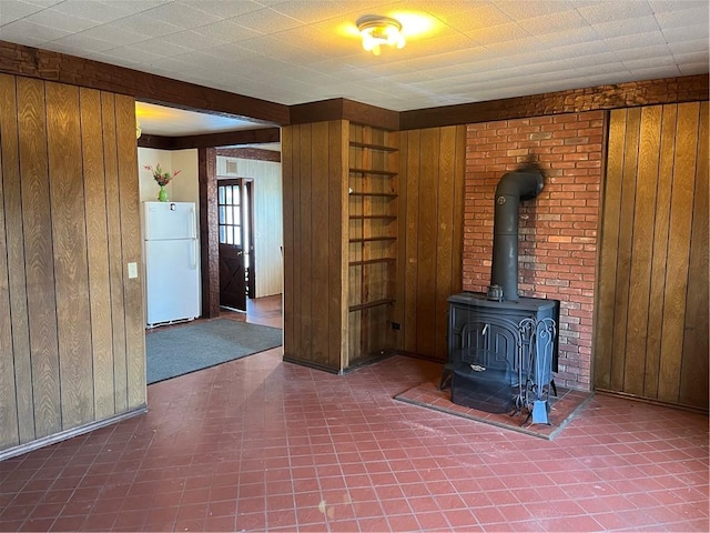 unfurnished living room with wood walls and a wood stove