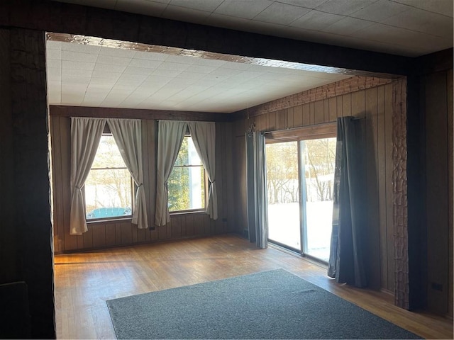 unfurnished room featuring hardwood / wood-style flooring, beam ceiling, and wooden walls