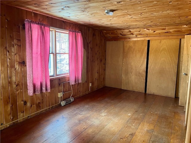 empty room with wooden walls, hardwood / wood-style flooring, and wooden ceiling