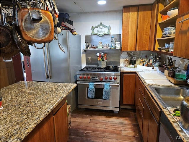 kitchen with light stone countertops, backsplash, stainless steel appliances, sink, and dark hardwood / wood-style floors