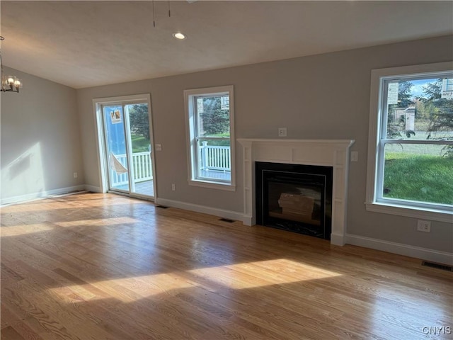 unfurnished living room featuring light wood-type flooring, vaulted ceiling, and a notable chandelier