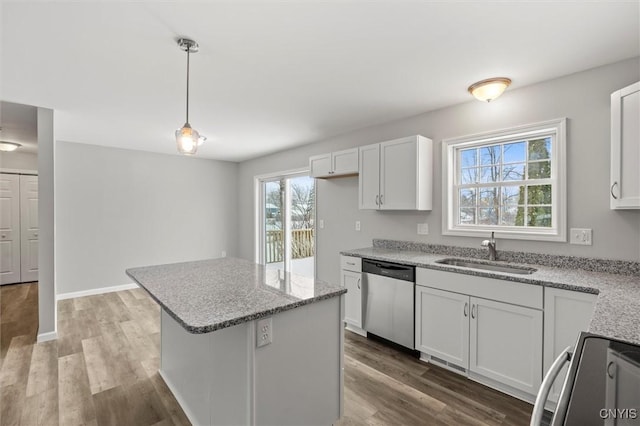 kitchen with appliances with stainless steel finishes, sink, wood-type flooring, decorative light fixtures, and white cabinets