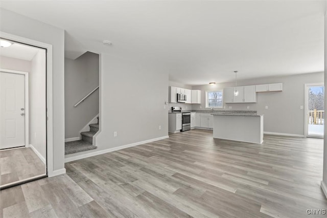 unfurnished living room featuring a wealth of natural light, sink, and light wood-type flooring