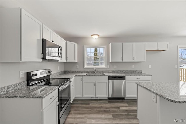 kitchen featuring sink, dark hardwood / wood-style floors, light stone counters, white cabinetry, and stainless steel appliances