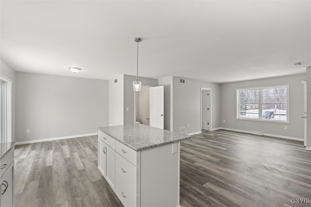 kitchen with white cabinets, pendant lighting, light stone countertops, and dark wood-type flooring