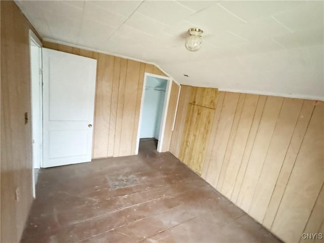 bonus room with wooden walls and vaulted ceiling