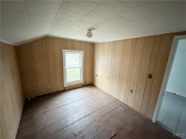 additional living space with hardwood / wood-style floors, lofted ceiling, and wooden walls