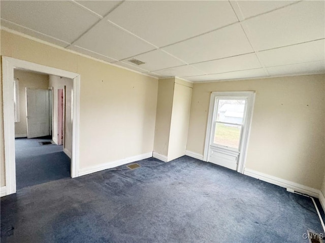 empty room featuring a paneled ceiling and dark carpet