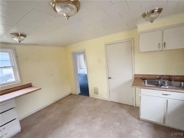 kitchen featuring light carpet, white cabinetry, and sink