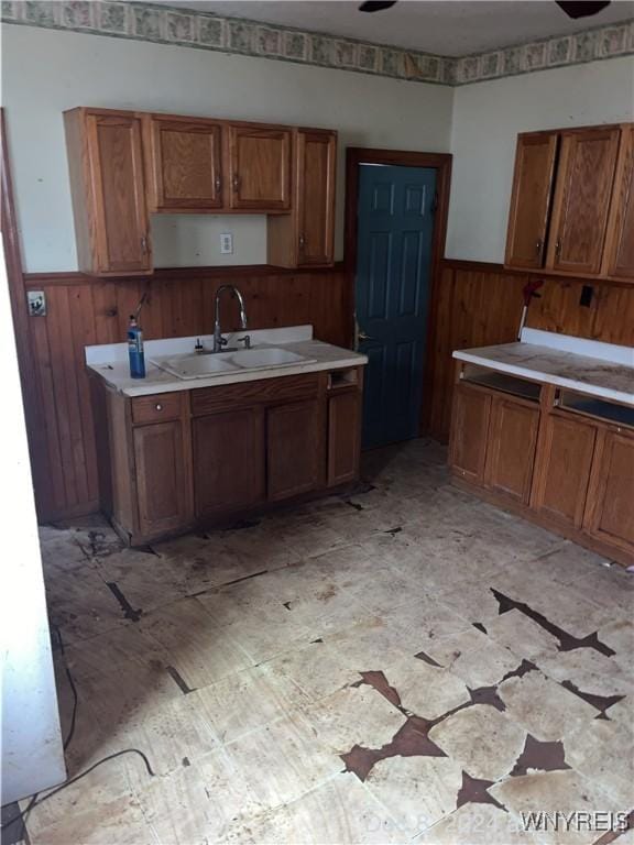 kitchen featuring ceiling fan, wood walls, and sink