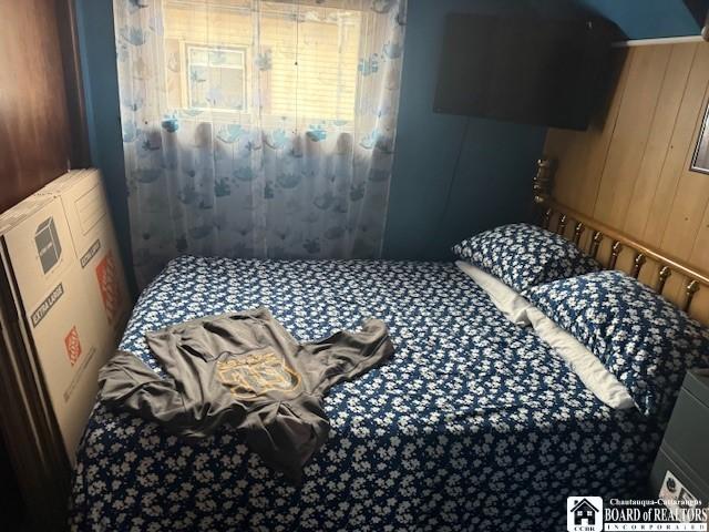 bedroom featuring wooden walls