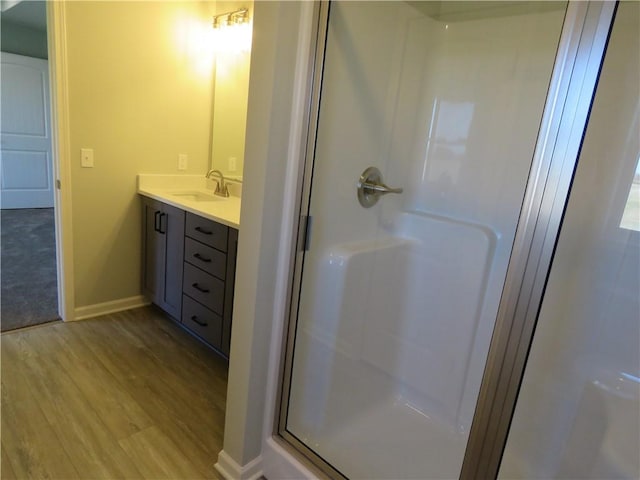 bathroom with vanity, hardwood / wood-style flooring, and a shower with door