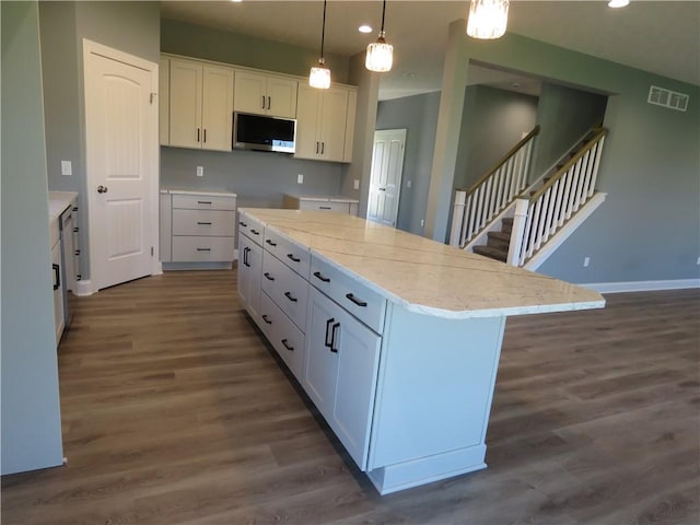 kitchen featuring white cabinetry, a kitchen island, hanging light fixtures, and dark hardwood / wood-style floors