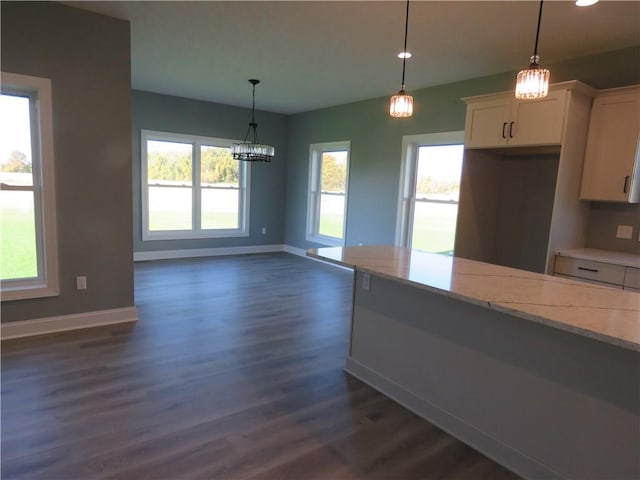 kitchen with white cabinetry, light stone countertops, dark hardwood / wood-style flooring, and hanging light fixtures