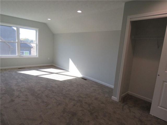 bonus room with dark colored carpet and vaulted ceiling