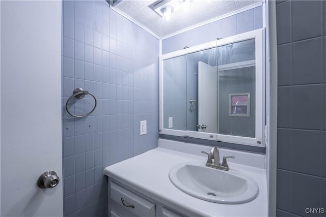 bathroom with vanity, ornamental molding, and tile walls