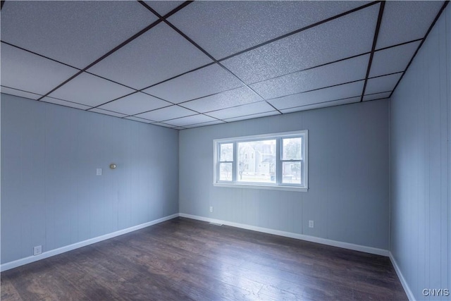 empty room with a drop ceiling and dark hardwood / wood-style flooring