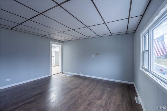 empty room featuring a drop ceiling and dark hardwood / wood-style floors